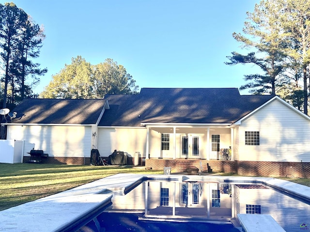 rear view of house featuring a yard, an outdoor pool, a patio, and french doors