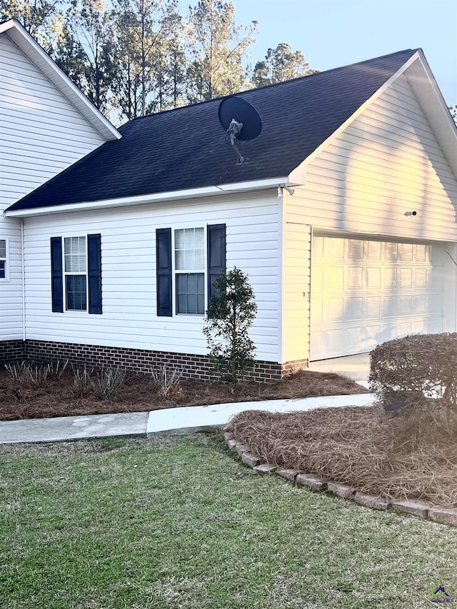 view of side of property with a garage, roof with shingles, and a lawn