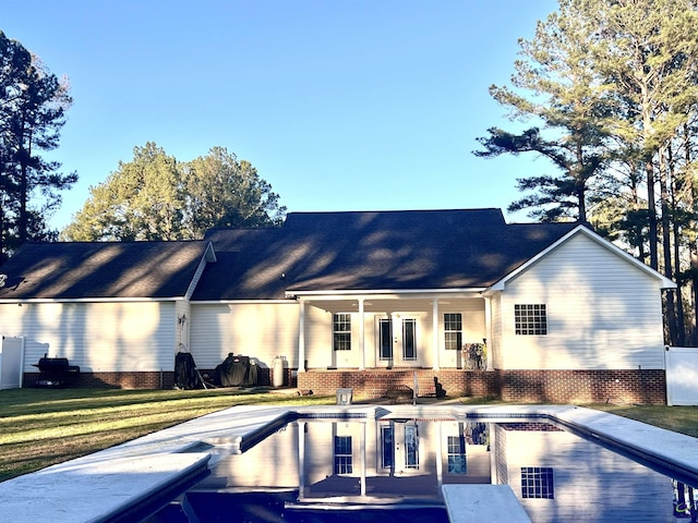 back of property featuring a yard and an outdoor pool