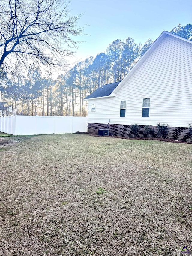 view of home's exterior with a mountain view, central AC, fence, and a lawn