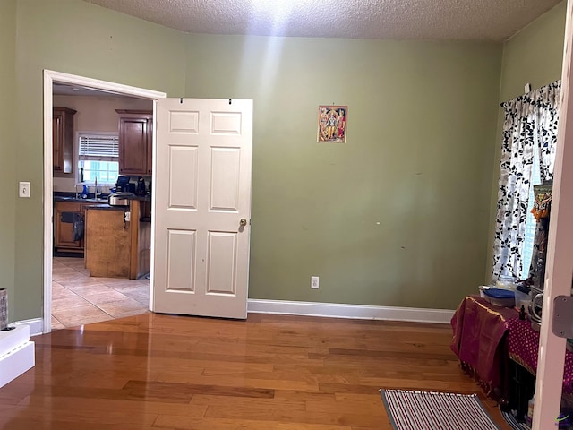 spare room with light wood-style flooring, baseboards, and a textured ceiling