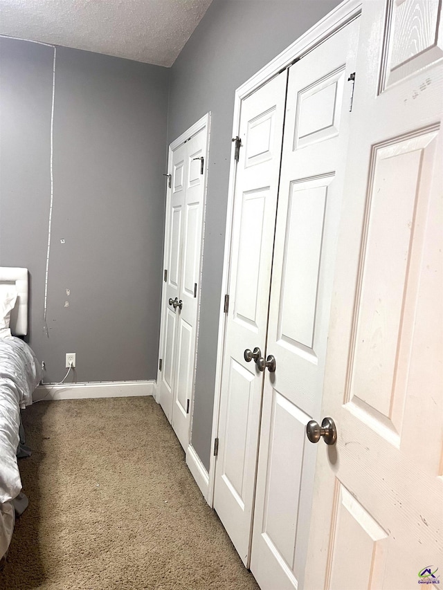 unfurnished bedroom with a textured ceiling, carpet floors, and baseboards