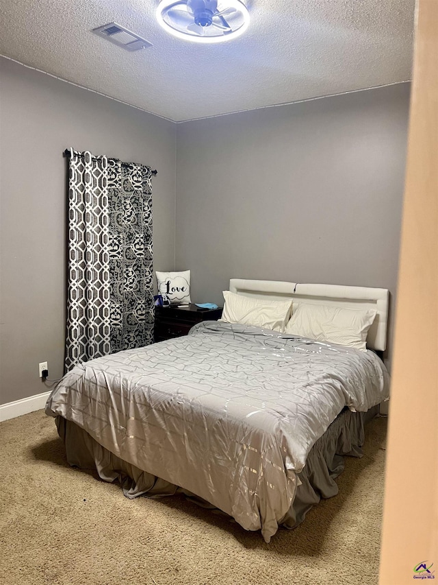 carpeted bedroom featuring a textured ceiling, visible vents, and baseboards