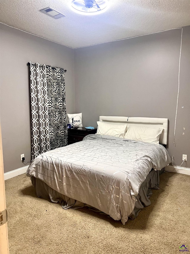 bedroom featuring a textured ceiling, carpet flooring, visible vents, and baseboards