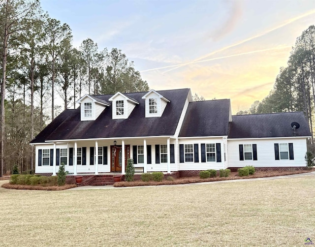 cape cod-style house with a porch and a lawn