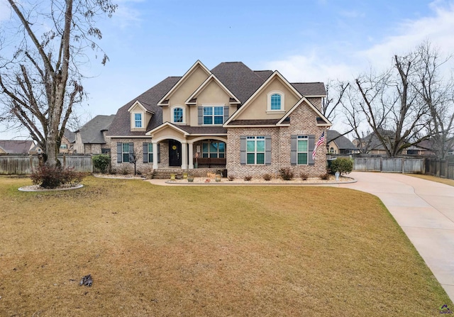 craftsman-style home featuring brick siding, a front yard, fence, and stucco siding