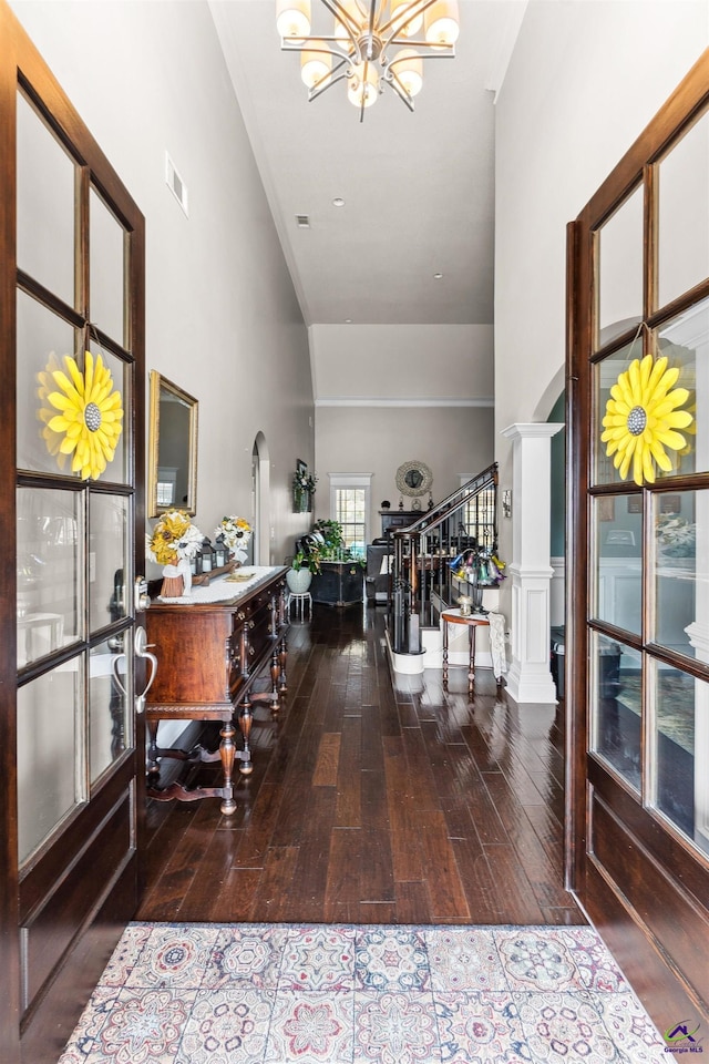 entryway featuring arched walkways, wood finished floors, stairs, and visible vents