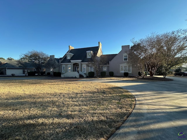 cape cod home with driveway and a front lawn