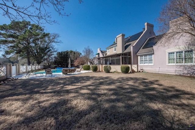 view of yard featuring a fenced in pool, a sunroom, fence, and a patio