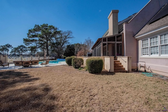 view of yard with a sunroom, a fire pit, and an outdoor pool