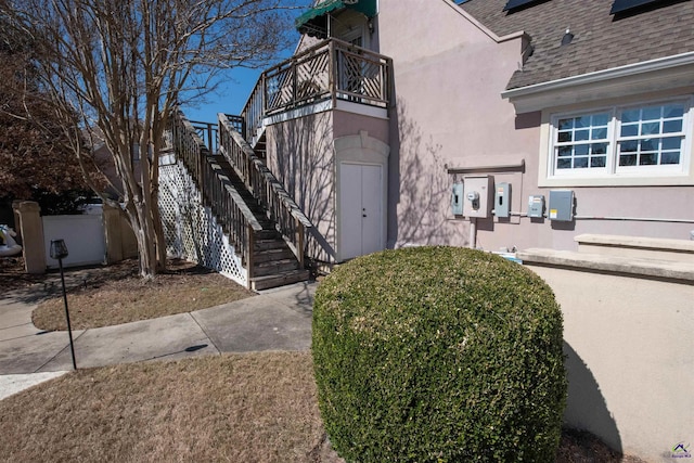 entrance to property with roof with shingles and stucco siding