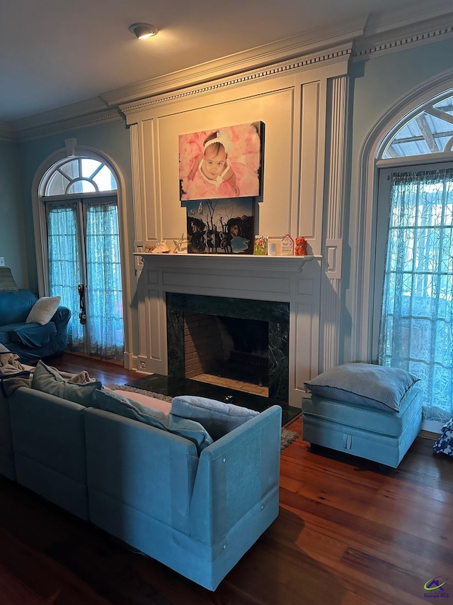 living area with a premium fireplace, dark wood-type flooring, crown molding, and french doors