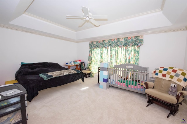 carpeted bedroom featuring a tray ceiling, a ceiling fan, and ornamental molding