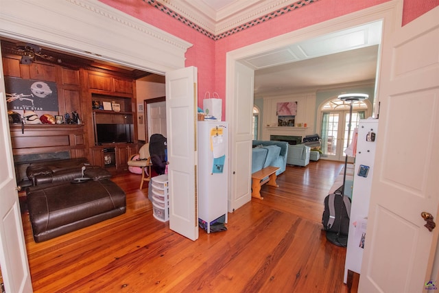 hall featuring water heater, built in shelves, wood finished floors, and crown molding