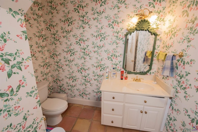 half bathroom with wallpapered walls, baseboards, toilet, tile patterned flooring, and vanity