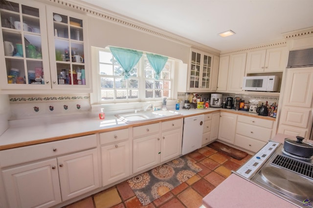 kitchen featuring light countertops, white appliances, a sink, and glass insert cabinets