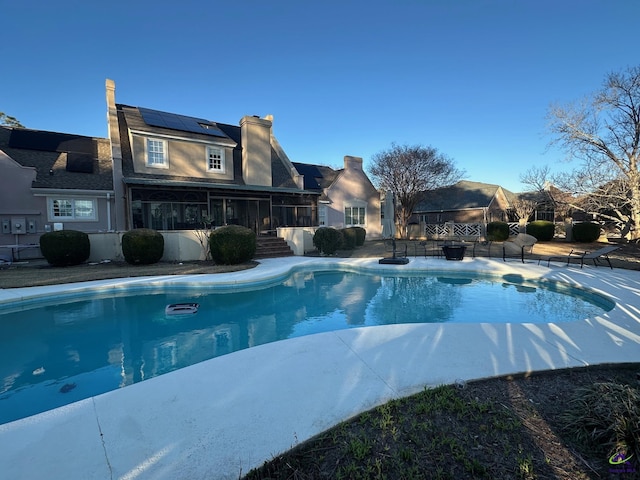 outdoor pool featuring a sunroom and a patio area