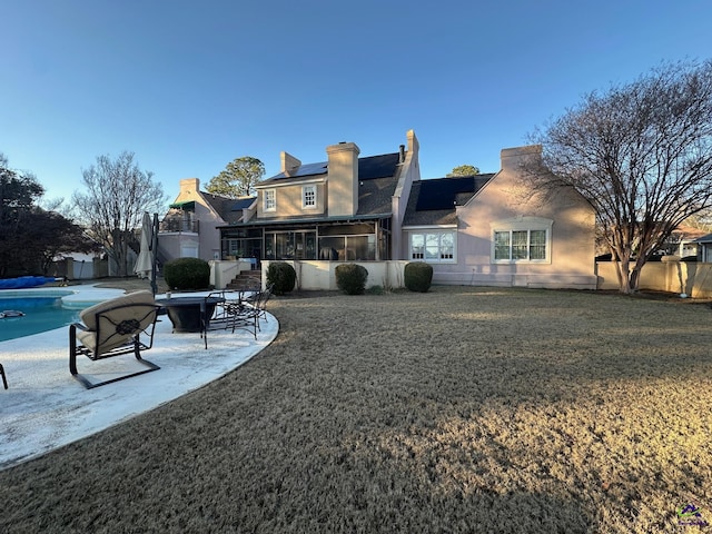 rear view of house featuring a fenced in pool, a lawn, a sunroom, a patio area, and fence