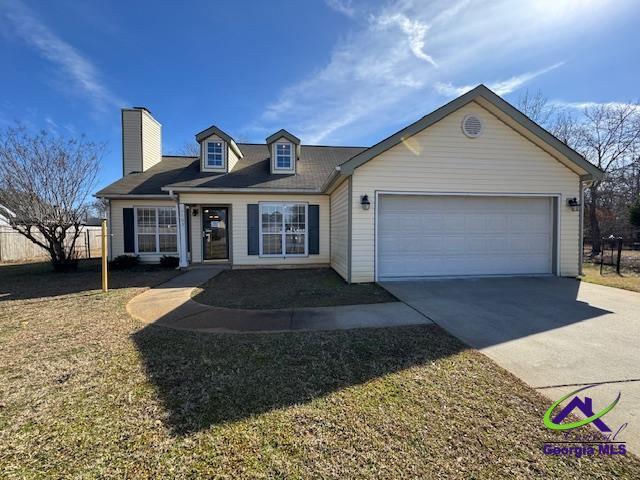 view of front of property with a garage, driveway, a chimney, and fence