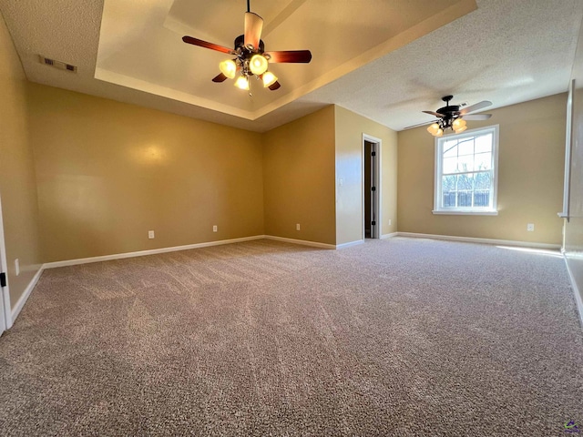 unfurnished room featuring baseboards, a textured ceiling, visible vents, and a tray ceiling