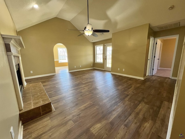 unfurnished living room with arched walkways, lofted ceiling, visible vents, a ceiling fan, and dark wood-style floors