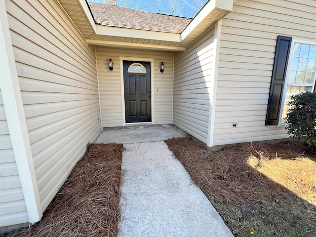 property entrance featuring a shingled roof and a chimney