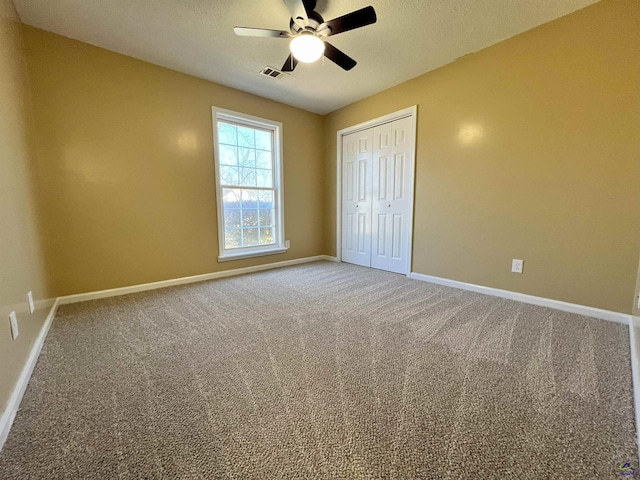 unfurnished bedroom with ceiling fan, carpet flooring, visible vents, baseboards, and a closet