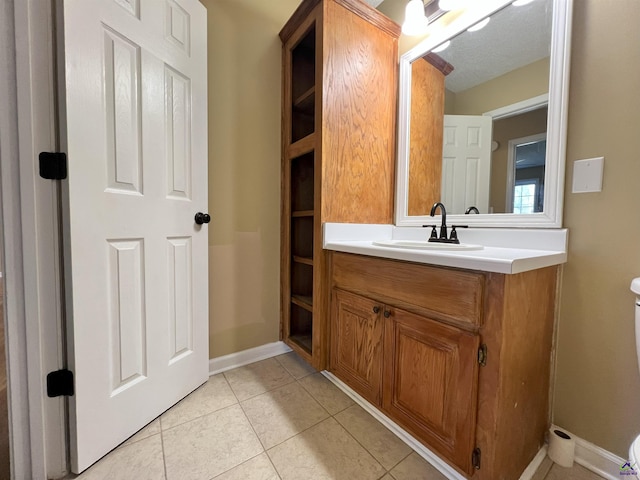 bathroom featuring baseboards, vanity, toilet, and tile patterned floors