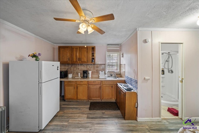 kitchen with dark wood-style flooring, light countertops, ornamental molding, freestanding refrigerator, and radiator