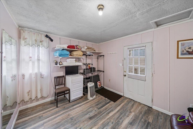 office space featuring a textured ceiling, dark wood-type flooring, baseboards, ornamental molding, and attic access