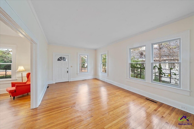 foyer with ornamental molding, light wood-type flooring, a healthy amount of sunlight, and visible vents