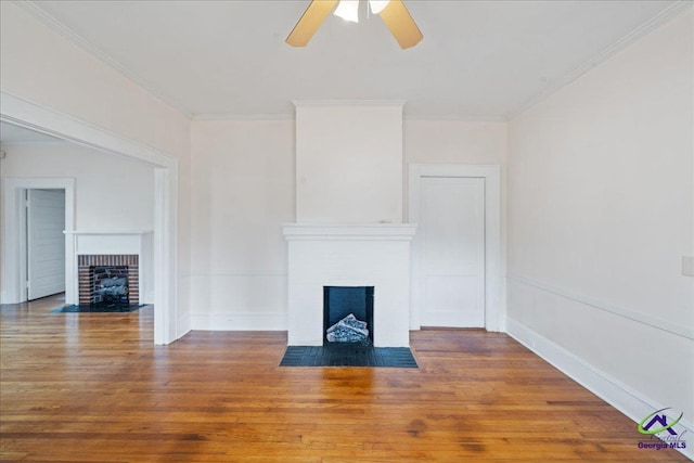 unfurnished living room featuring a fireplace with flush hearth, ornamental molding, ceiling fan, and wood finished floors