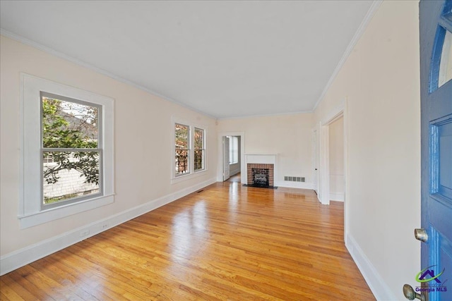 unfurnished living room featuring a fireplace, light wood finished floors, visible vents, ornamental molding, and baseboards