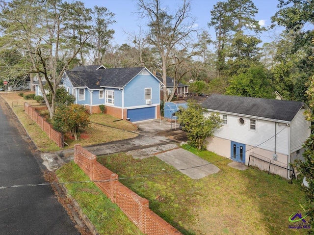 view of front of home featuring a garage, concrete driveway, a front yard, and fence