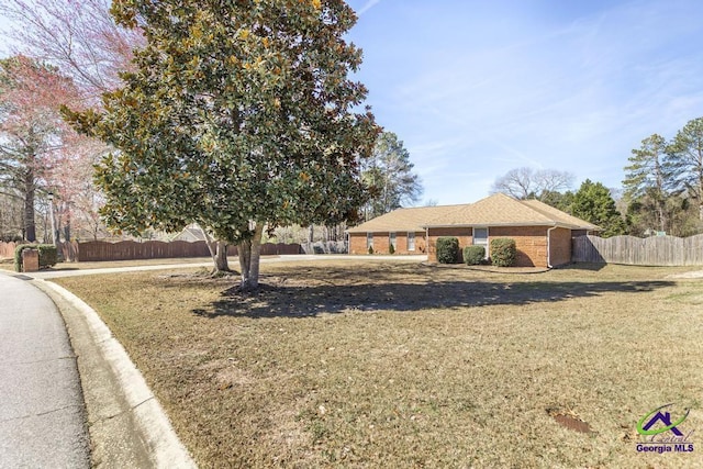 ranch-style house featuring a front yard, fence, and brick siding