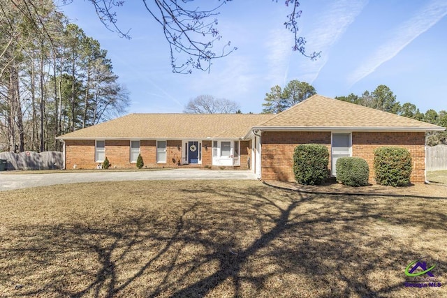 ranch-style home with brick siding, a shingled roof, and fence