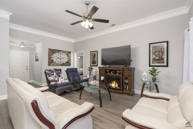 living room featuring a warm lit fireplace, ceiling fan, wood finished floors, and visible vents