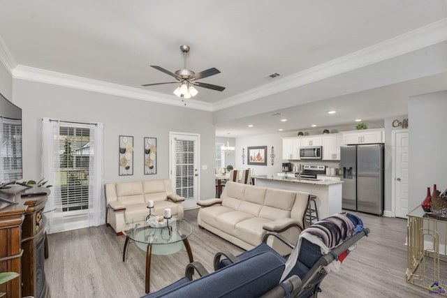 living area with recessed lighting, ceiling fan with notable chandelier, visible vents, ornamental molding, and light wood-type flooring