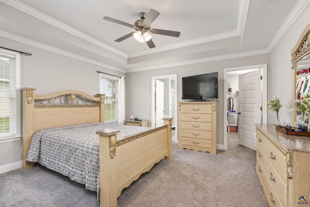 bedroom featuring light colored carpet, a ceiling fan, baseboards, ornamental molding, and a raised ceiling