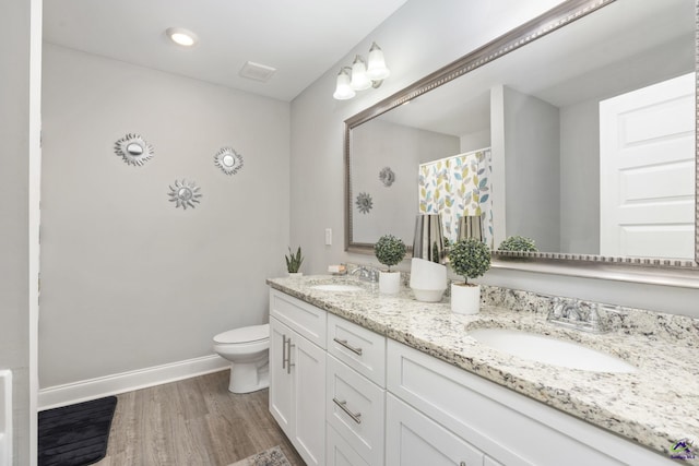 bathroom featuring toilet, a sink, baseboards, and wood finished floors