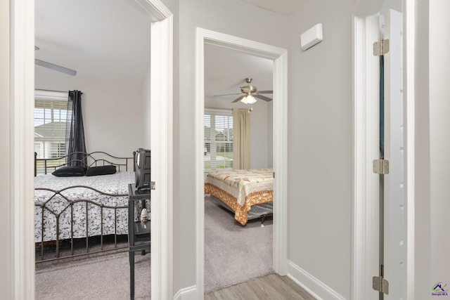 hall featuring carpet, baseboards, and wood finished floors