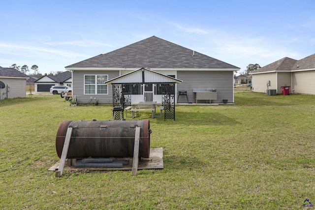 back of house with a yard, roof with shingles, and central air condition unit