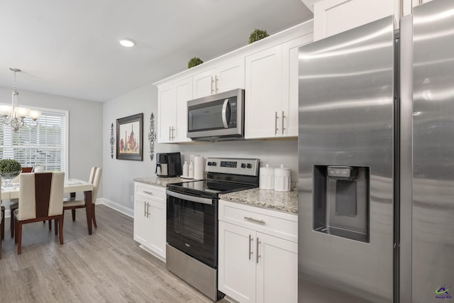 kitchen with light stone counters, light wood-style flooring, white cabinetry, appliances with stainless steel finishes, and pendant lighting