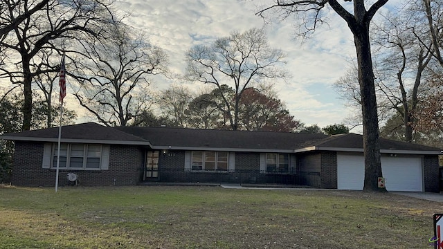 ranch-style house with a garage, concrete driveway, brick siding, and a front yard