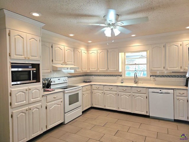 kitchen featuring tasteful backsplash, light countertops, a sink, white appliances, and under cabinet range hood