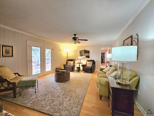 living area with french doors, crown molding, light wood-style floors, ceiling fan, and a textured ceiling