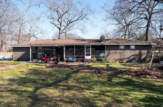 rear view of house with a sunroom, a chimney, a lawn, and brick siding