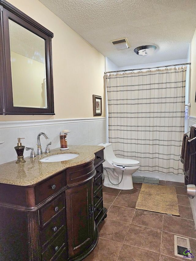 full bath featuring visible vents, tile walls, and a textured ceiling