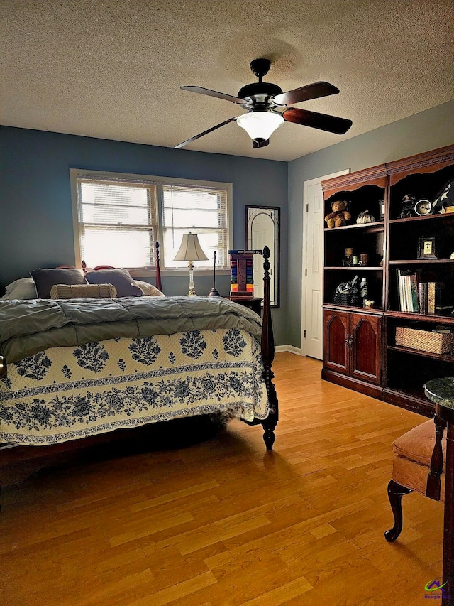 bedroom with light wood-style flooring, a ceiling fan, and a textured ceiling