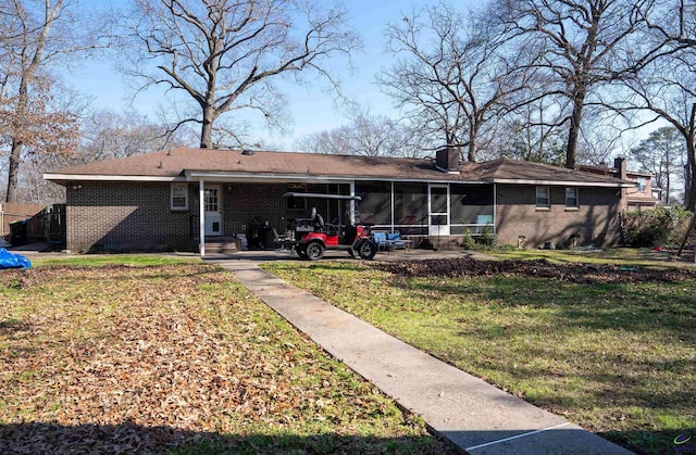 rear view of house with a sunroom, brick siding, and a lawn